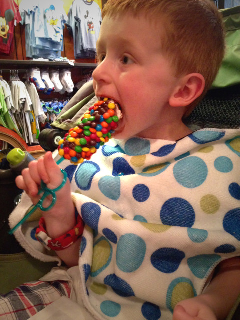 Boy eats chocolate covered candy on a stick