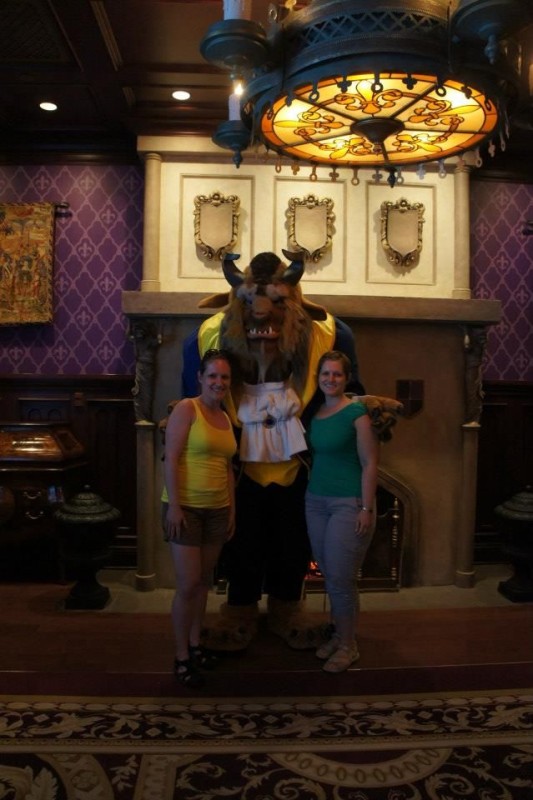 Two women posing with Beast in his library